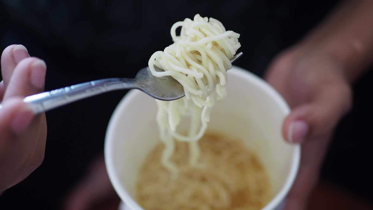Close-up of a Fork Picking Up Ramen Noodles from a Cup
