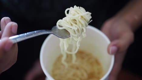 close-up of a fork picking up ramen noodles from a cup