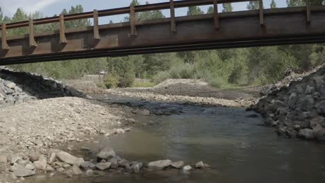 Aerial-drone-shot---slow-fly-under-bridge-over-creek