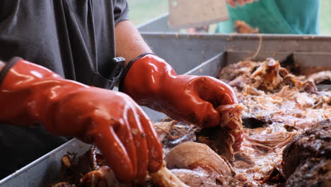 hombre sacando barbacoa de cerdo de un cerdo cocido