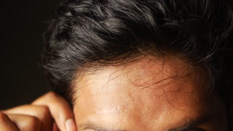 close-up of a person's forehead and hair with visible sweat