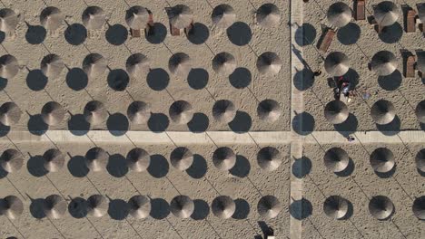 antena de arena ascendente revela un patrón geométrico de sombrillas de playa de hierba