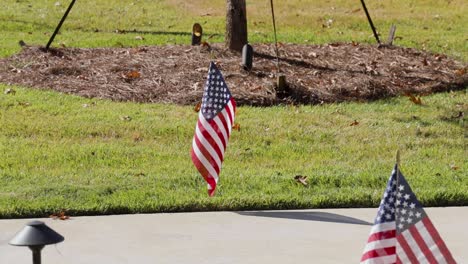 Solitary-small-American-flag-waving-on-sidewalk