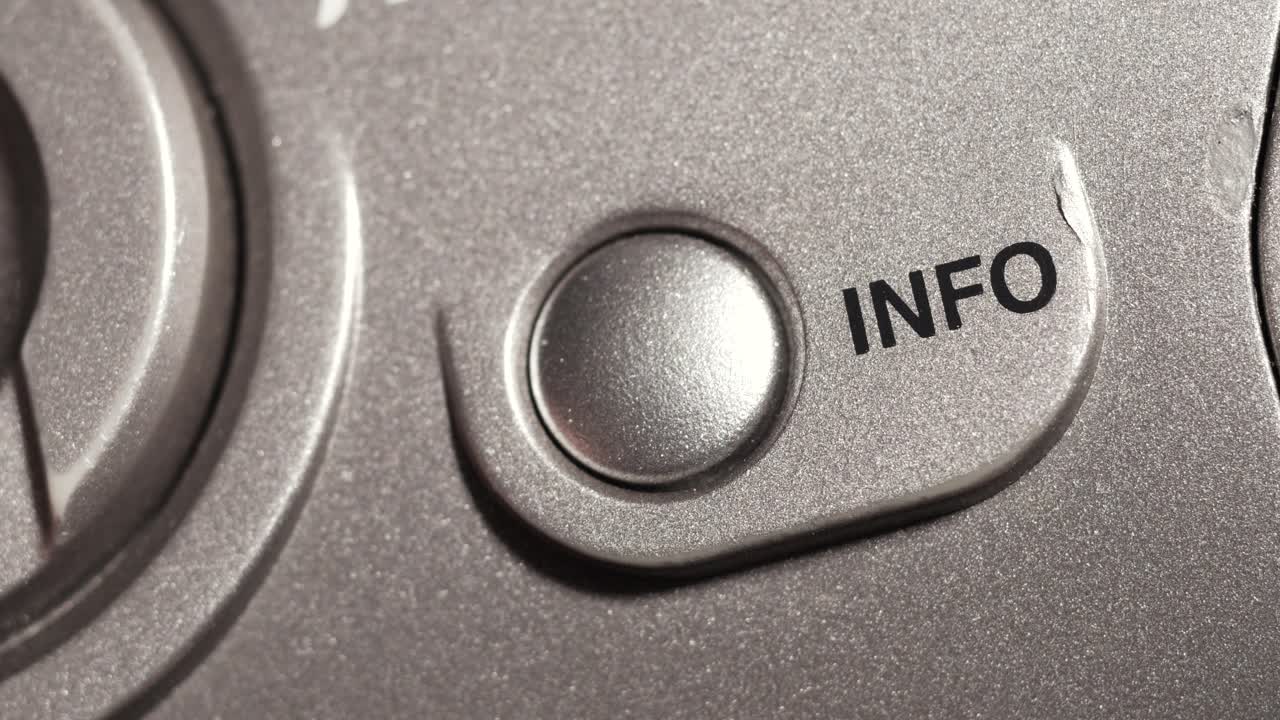 Macro close up of info button pressed on metallic silver panel with black lettering