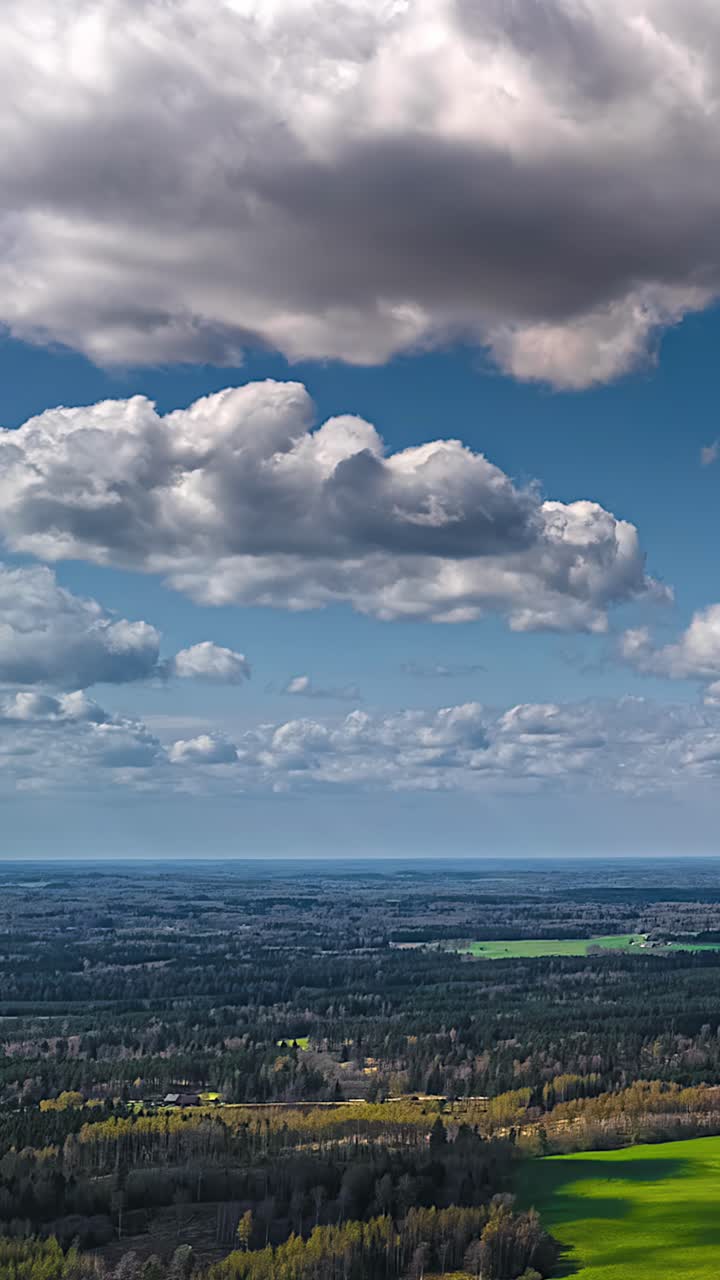 Vertical timelapse of clouds over green fields, adding depth and serenity