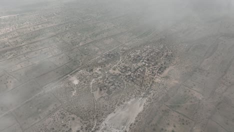 aerial drone shot flying high over desert life in a tiny village in tharparkar, sindh, pakistan on a cloudy day