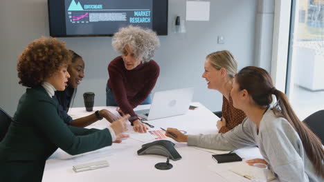 Empresaria-Madura-Liderando-Una-Reunión-Creativa-De-Mujeres-Colaborando-Alrededor-De-Una-Mesa-En-Una-Oficina-Moderna