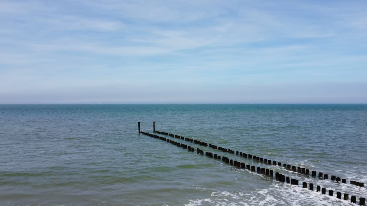 Long groyne reaching into the sea at a beach in the Netherlands