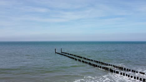 largo groyne que llega al mar en una playa en los países bajos