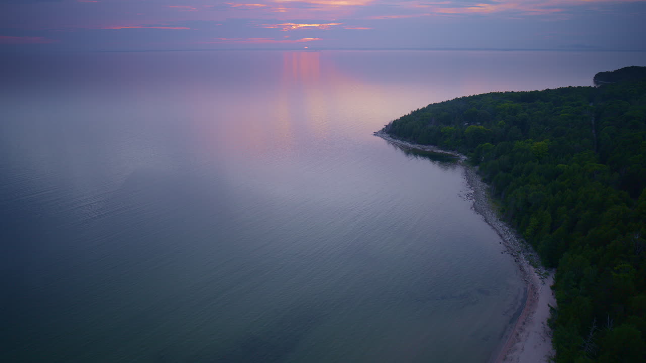 Drone shot flying up the coast of lake michigan near fayette historic state park just sun is about to set on the horizon