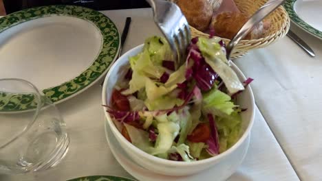 tossing salad at a dining table