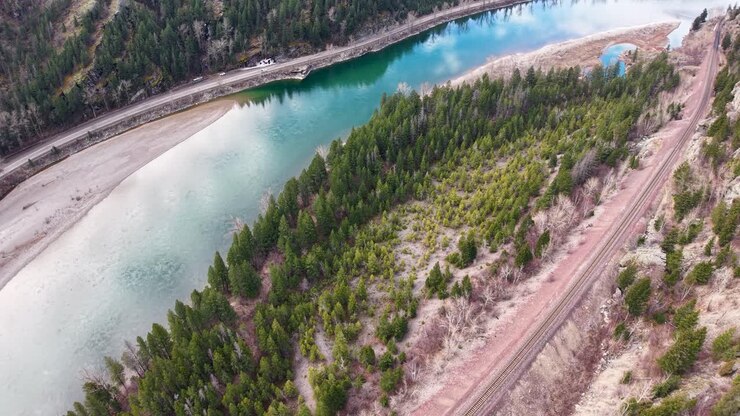 Veduta aerea con drone del fiume Flathead turchese che si snoda tra foreste sempreverdi e sponde rocciose in una zona selvaggia e remota vicino a Whitefish, Montana.
