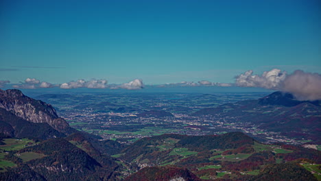 Timelapse-of-impressive-wide-valley-in-Berchtesgaden,-Austria-from-the-viewing-platform-at-the-Eagle's-Nest-with-views-of-majestic-mountain-ranges-surrounded-by-meadows-and-fields-with-passing-clouds