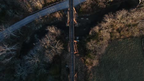 aerial top down shot of the pope lick railroad trestle and the surrounding woods and stream during sunset in louisville kentucky