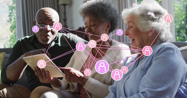 Four seniors tapping tablet to start network icons expanding to link faces in technology demo