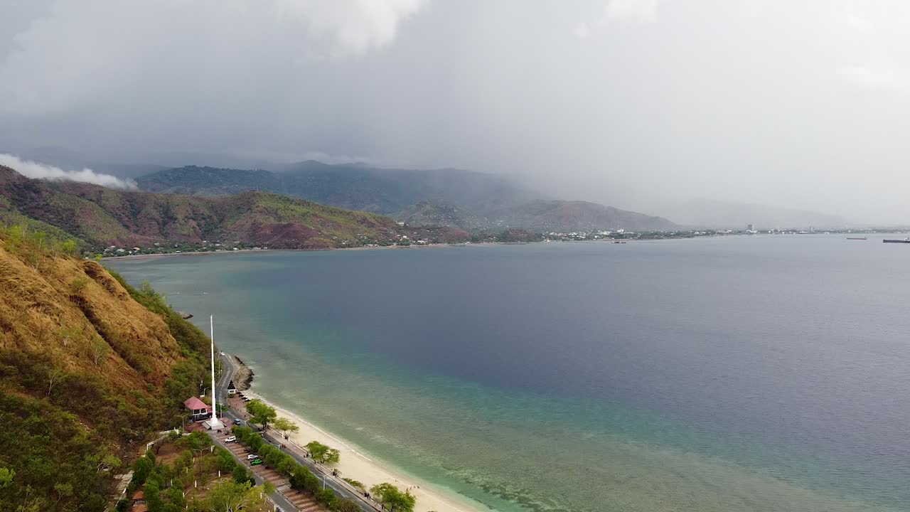 Scenic aerial view overlooking white sandy beach, ocean, and rugged mountainous hills in capital city Dili, Timor-Leste, Southeast Asia