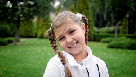 young girl with brown eyes and hair in pigtails smiling at the camera