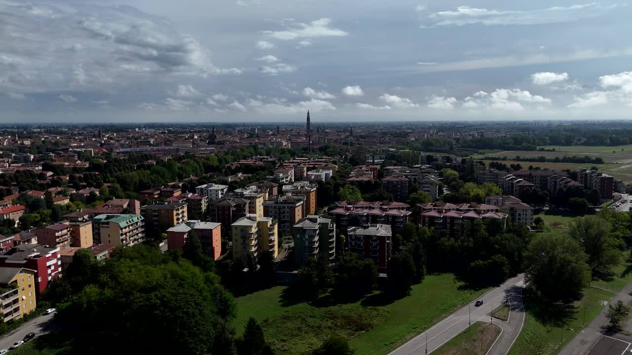 Panoramic drone aerial view of Cremona a historic city in Lombardy Italy showcasing its urban landscape and distant iconic landmarks under a cloudy sky