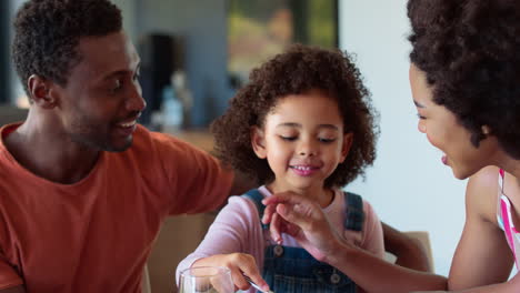 Family-Shot-With-Parents-And-Daughter-At-Home-Having-Breakfast-Spreading-Jam-On-Bread-At-Table