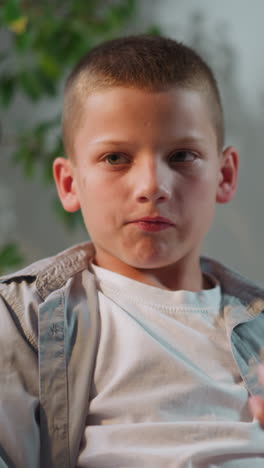 boy finishes talking with mom turning to camera and smiling. cute schoolboy ends phone call relaxing on comfortable couch in living room closeup