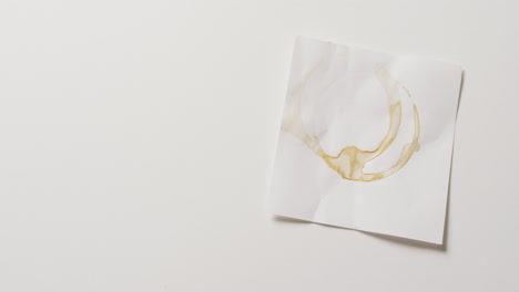 vídeo close-up de um pedaço de papel com manchas de anel de xícara de café em fundo branco