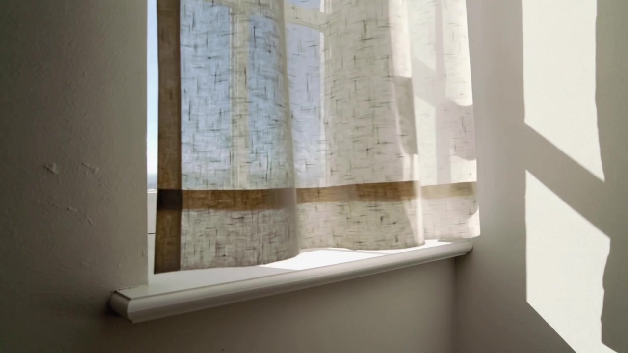 Swaying sheer patterned curtain by breeze at window, revealing blue sky and shifting light