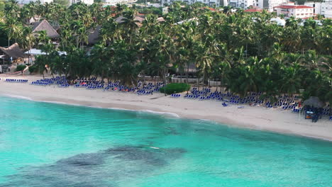 Aerial-shot-of-scenery-Bayahibe-beach-at-sunny-day,-where-people-enjoys-vacation-on-clear-Caribbean-sea-shore-in-Dominican-Republic