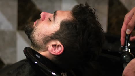 peluquero lavando el cabello de los clientes