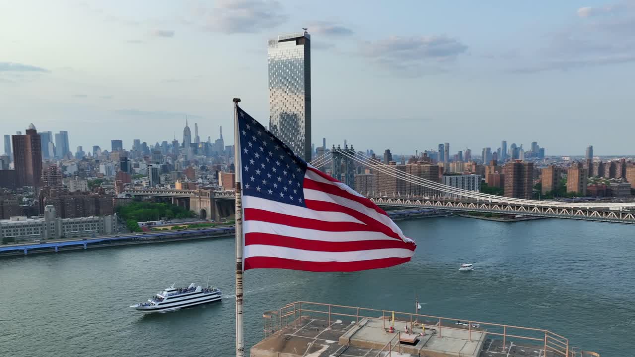 la bandera estadounidense ondeando con orgullo frente al puente de manhattan y el centro de la ciudad de nueva york