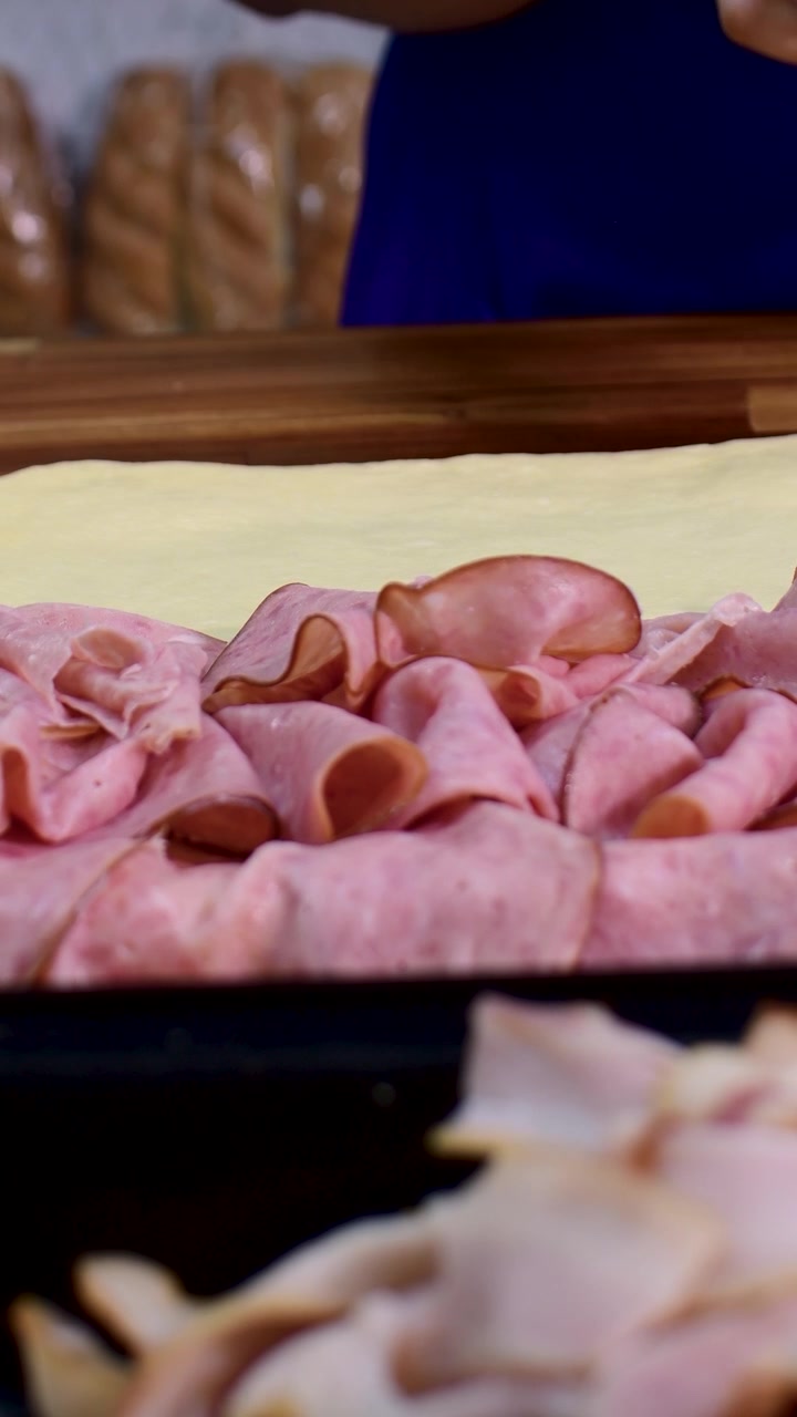 Primo piano di prosciutto a fette su pasta sfoglia fresca per la preparazione della cottura