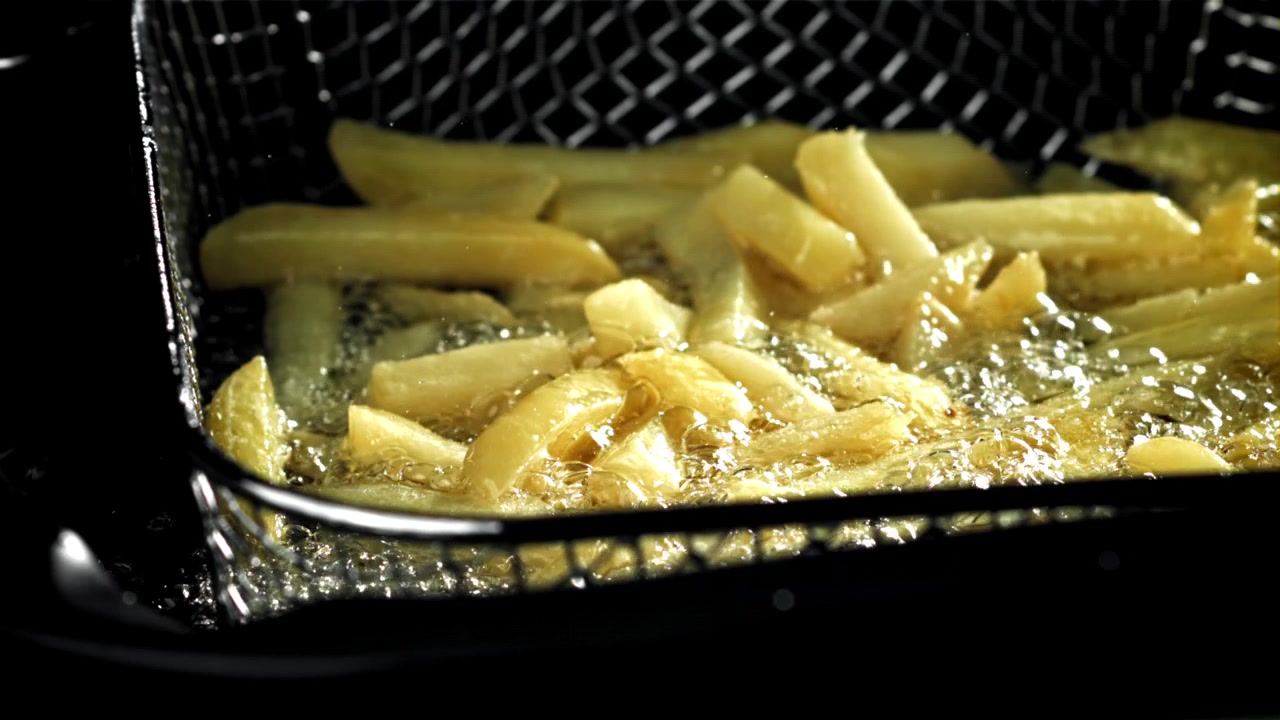 Primer plano de patatas fritas doradas friéndose en aceite caliente