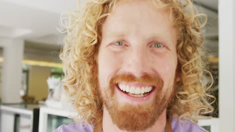 Portrait-close-up-of-happy-caucasian-male-barista-smiling-in-his-coffee-shop