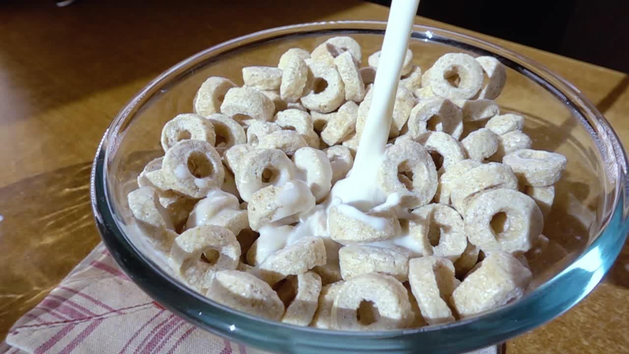 copos de avena crujientes en un tazón para un delicioso desayuno matutino con leche. cámara lenta con toma de seguimiento de rotación.
