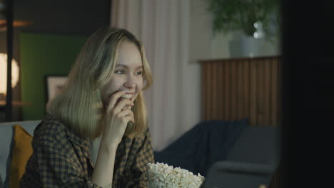 woman watching tv and eating popcorn