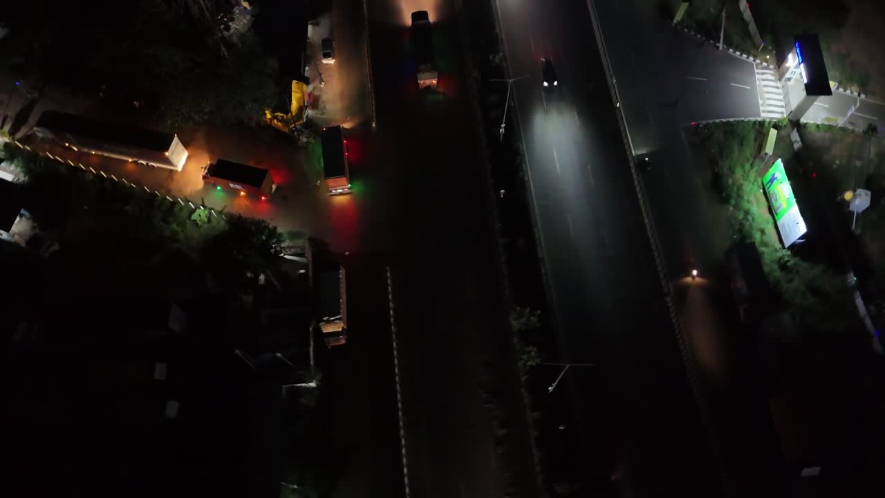 High-angle stock video of a brightly lit divided highway contrasting with the dark surroundings. Perfect for speed, motion, and road network visuals