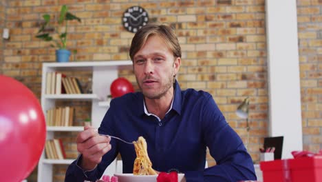 portrait of caucasian man having food on videocall at home