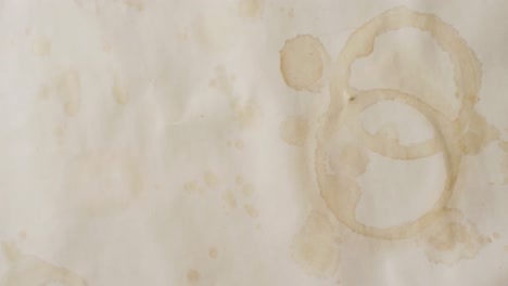 video of close up of piece of paper with round coffee mug stains on white background