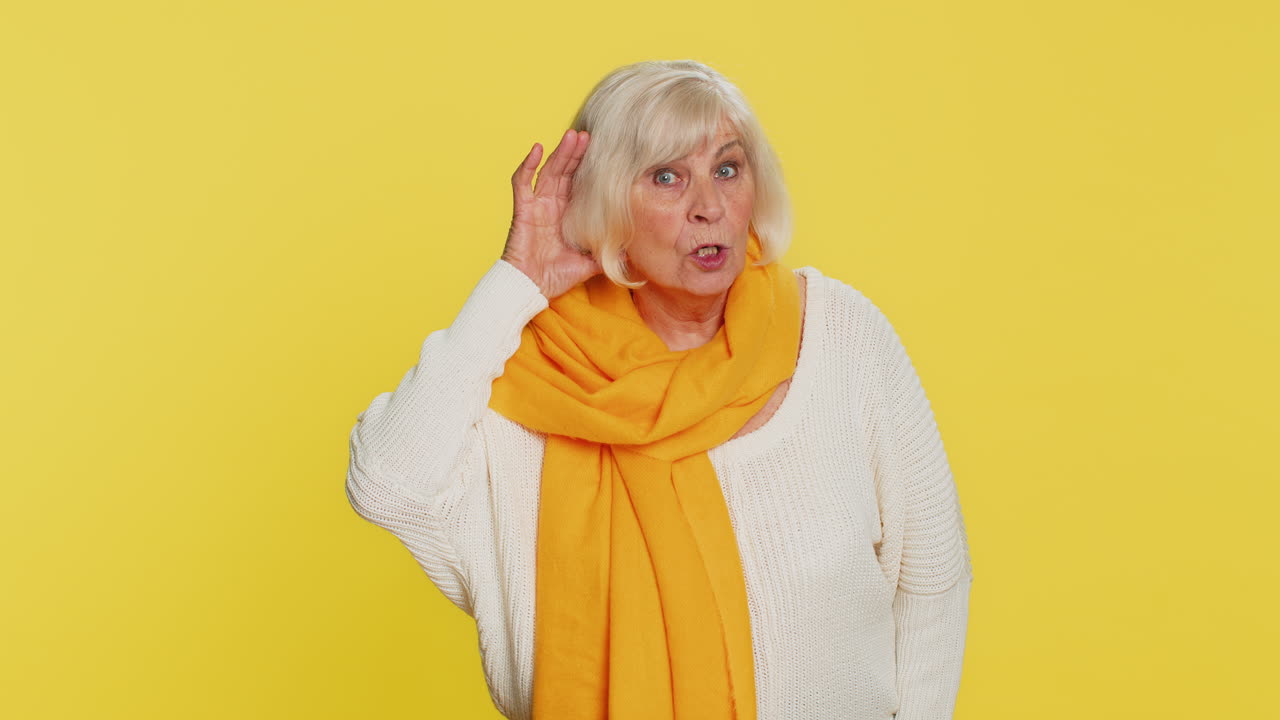anciana tratando de oírte mirando confusa y fruncido el ceño manteniendo el brazo cerca de la oreja para una voz más alta