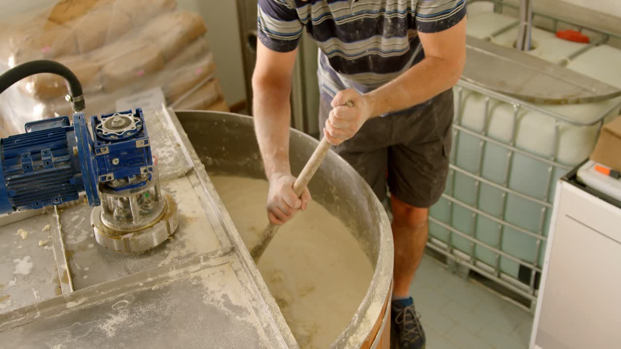 мужчина-рабочий перемешивает джин в дистилляторе 4k