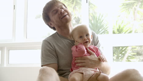 happy father holding baby on hands, playing, talking with girl