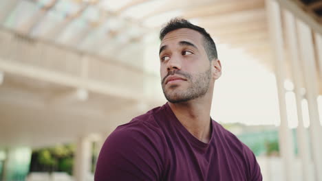 Young-man-looking-around-while-sitting-outdoors.