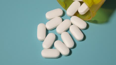 Píldoras-Blancas-Opioides-Derramadas-Sobre-La-Mesa-Para-La-Adicción-A-La-Salud-Medicina-Para-El-Dolor-Fondo-Verde-Azulado