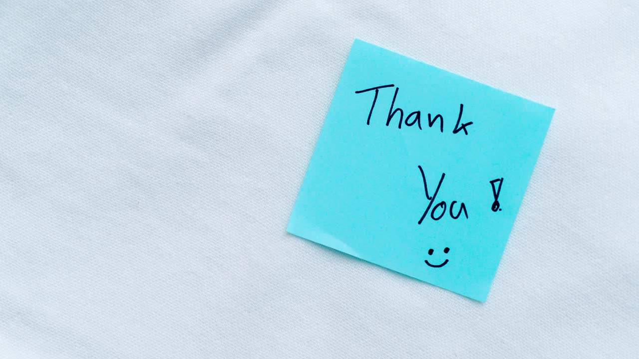 A close-up view of a blue sticky note with a heartfelt message of gratitude emphasizing appreciation and simplicity.