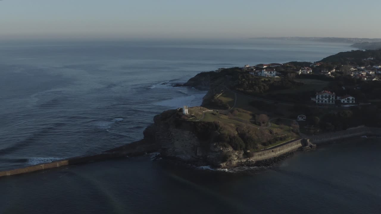 Sainte-Barbe chapel perched on rugged cliffs overlooking Atlantic Ocean at sunset, Saint-Jean-de-Luz, France. Aerial drone panoramic view, copy space