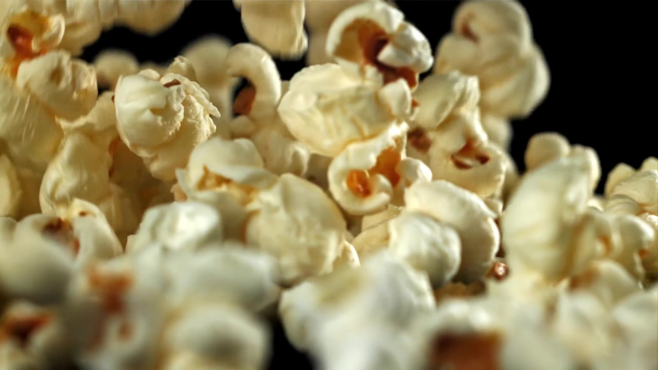 Primo piano di popcorn che cade su sfondo nero al rallentatore