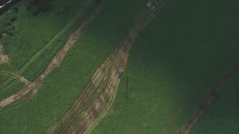 aerial view of a vehicle on a dirt road through a grassy field