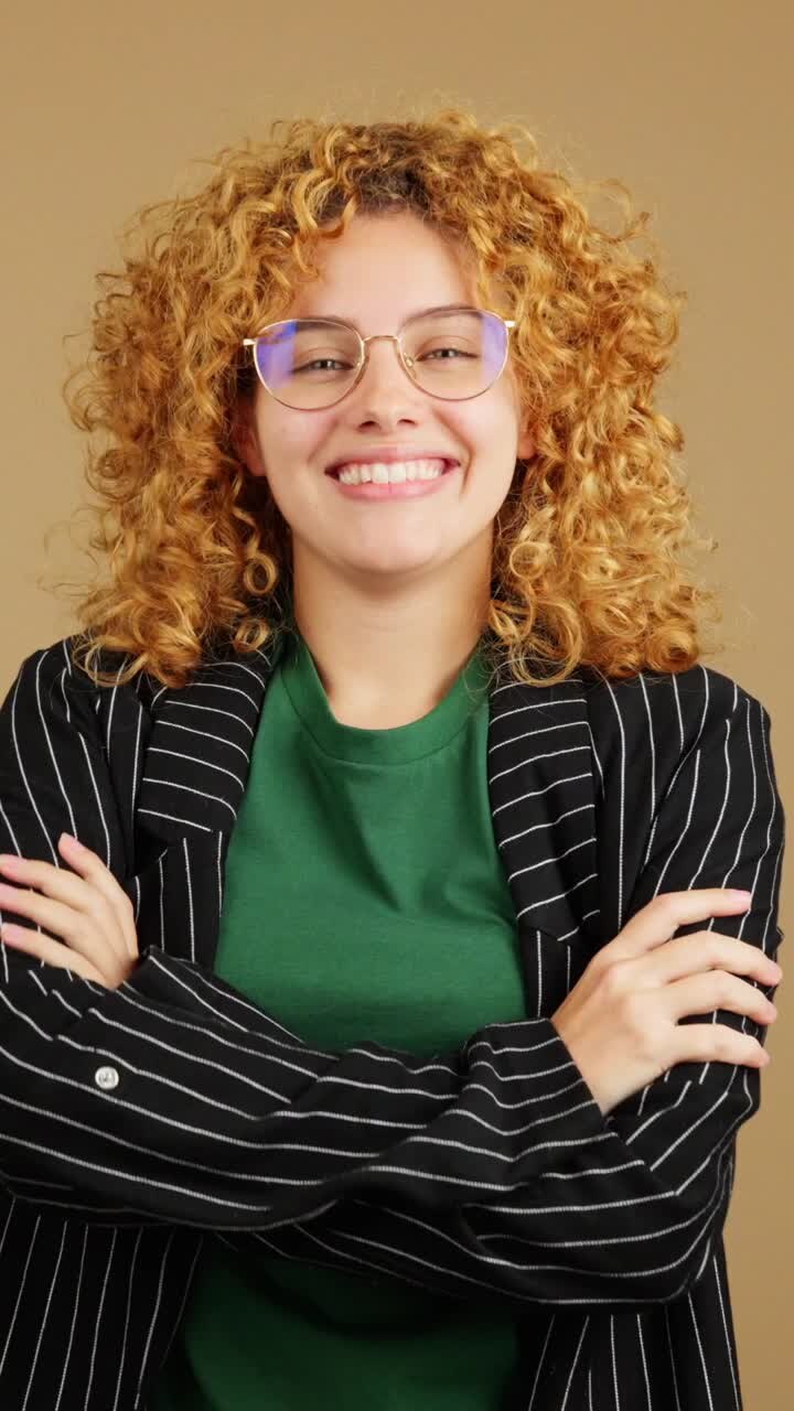 Giovane donna con capelli ricci e occhiali che sorride felicemente