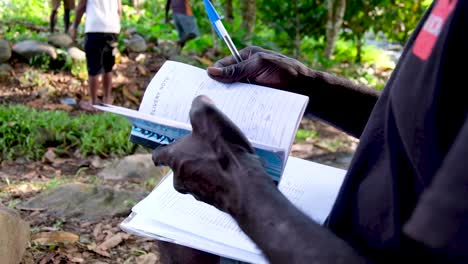 Hombre-Trabajando-Afuera-Con-Un-Talonario-De-Recibos-En-Bougainville,-Papua-Nueva-Guinea