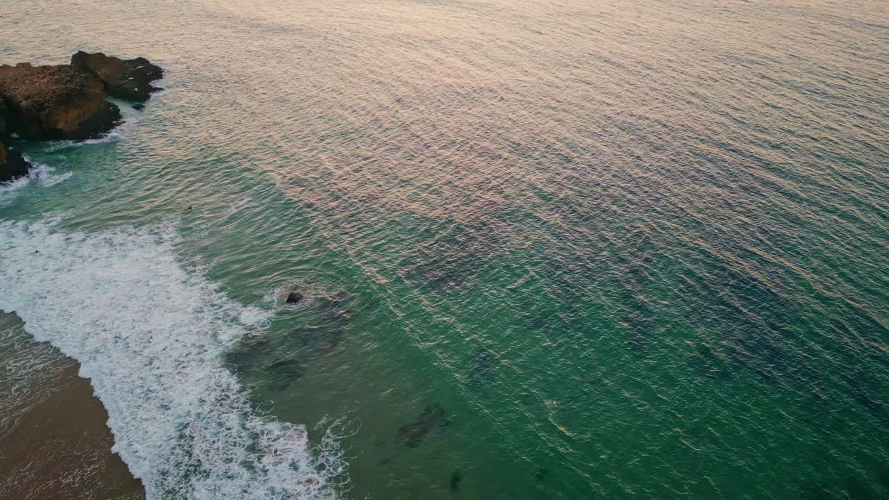 Drone ocean waves washing coastline. Peaceful scenic landscape on golden sunset