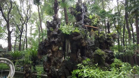 Footage-of-a-artificial-small-waterfall-flowing-from-a-rock-in-a-traditional-Chinese-garden-at-the-Wenshu-Monastery,-Chengdu,-Sichuan-Province,-China